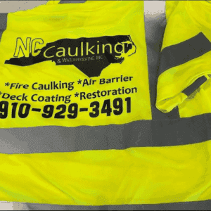 A hi-vis safety vest printed with the NC Caulking and Waterproofing logo and phone number