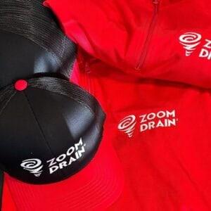 Zoom Drain branded workwear: a red quarter-zip, a red polo and a black trucker cap
