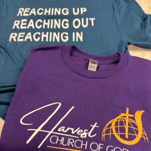 A purple Harvest Church of God crewneck sweatshirt layered over a teal printed tee