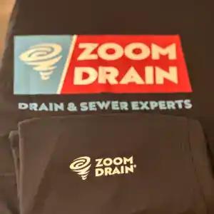 A Zoom Drain softshell jacket with an embroidered chest logo, folded over matching branded workwear