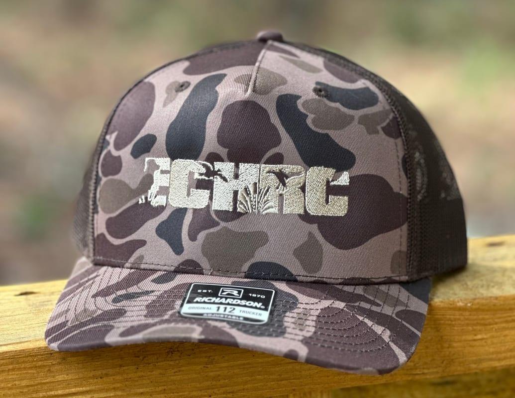 A camouflage trucker cap with an ECHRC monogram embroidered in tan