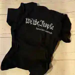 A black tee screen printed with We the People have had enough in blackletter type