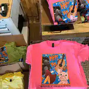 Neon pink tees on the screen printing press, printed with a full colour graphic