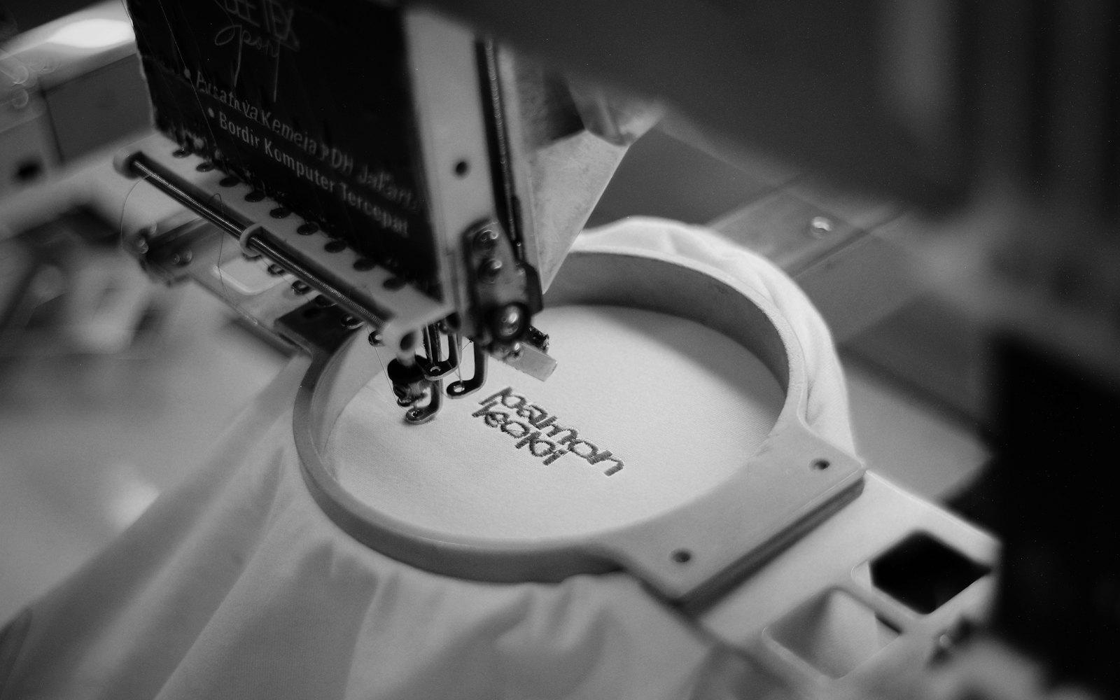 An embroidery machine stitching a logo into a hooped shirt