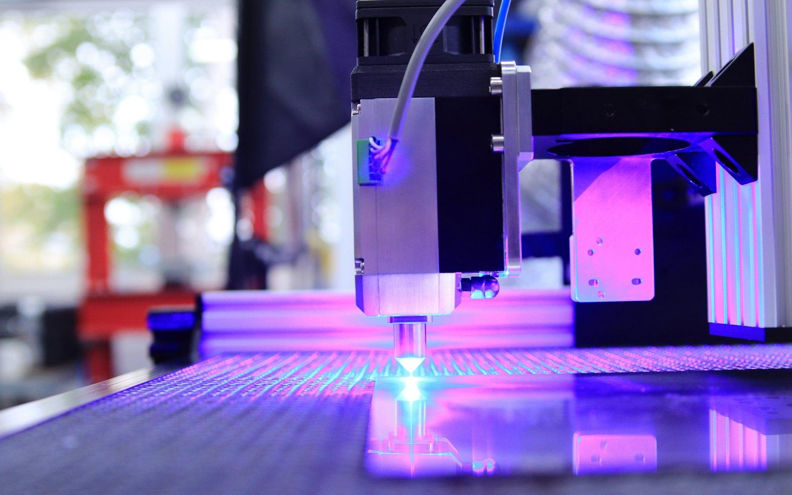 A laser engraver cutting a design into a flat sheet
